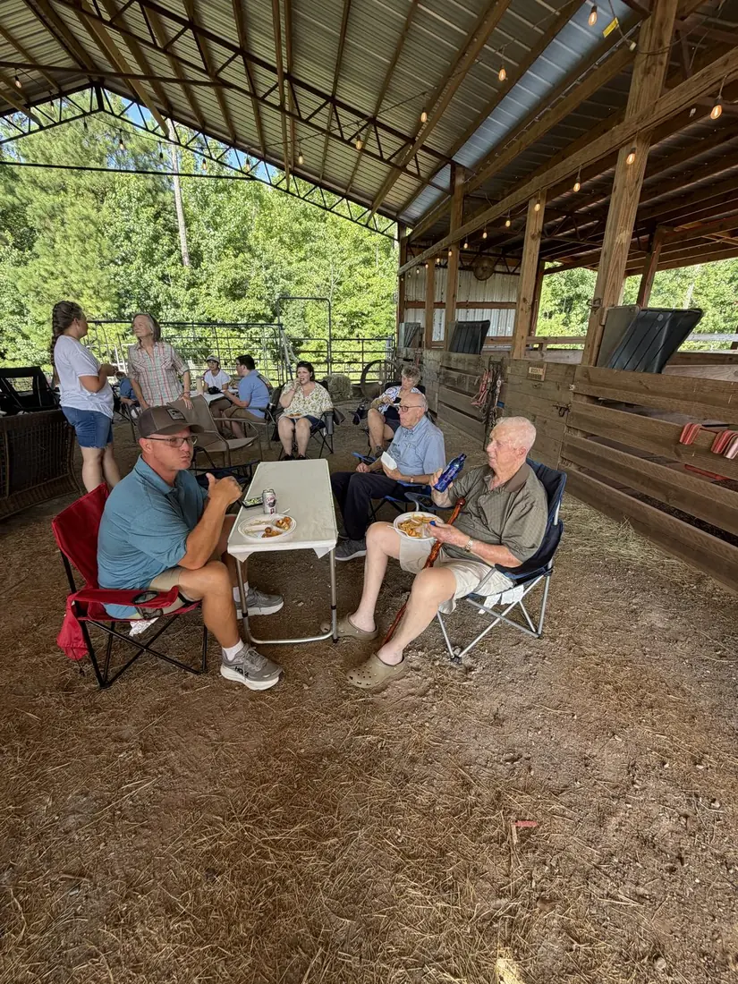 Family gathered around a shaded table with hot dogs and cold drinks
