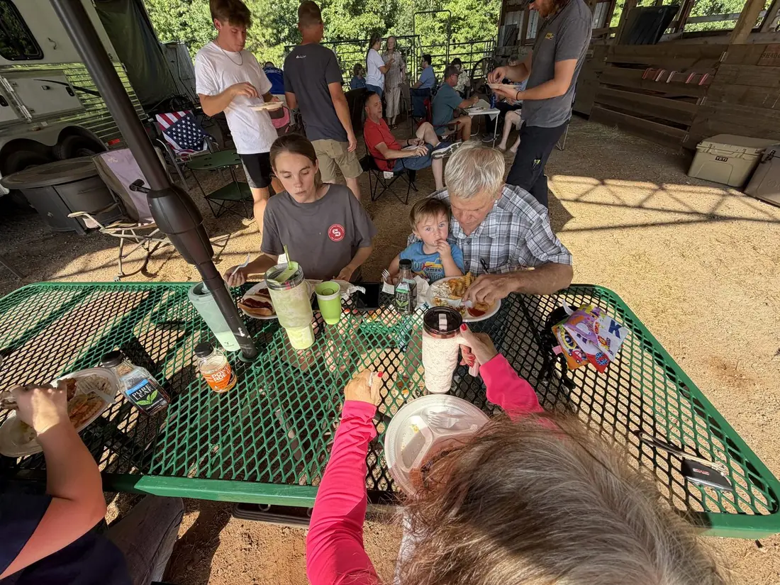 Friends relaxing in camp chairs with plates of fried fish