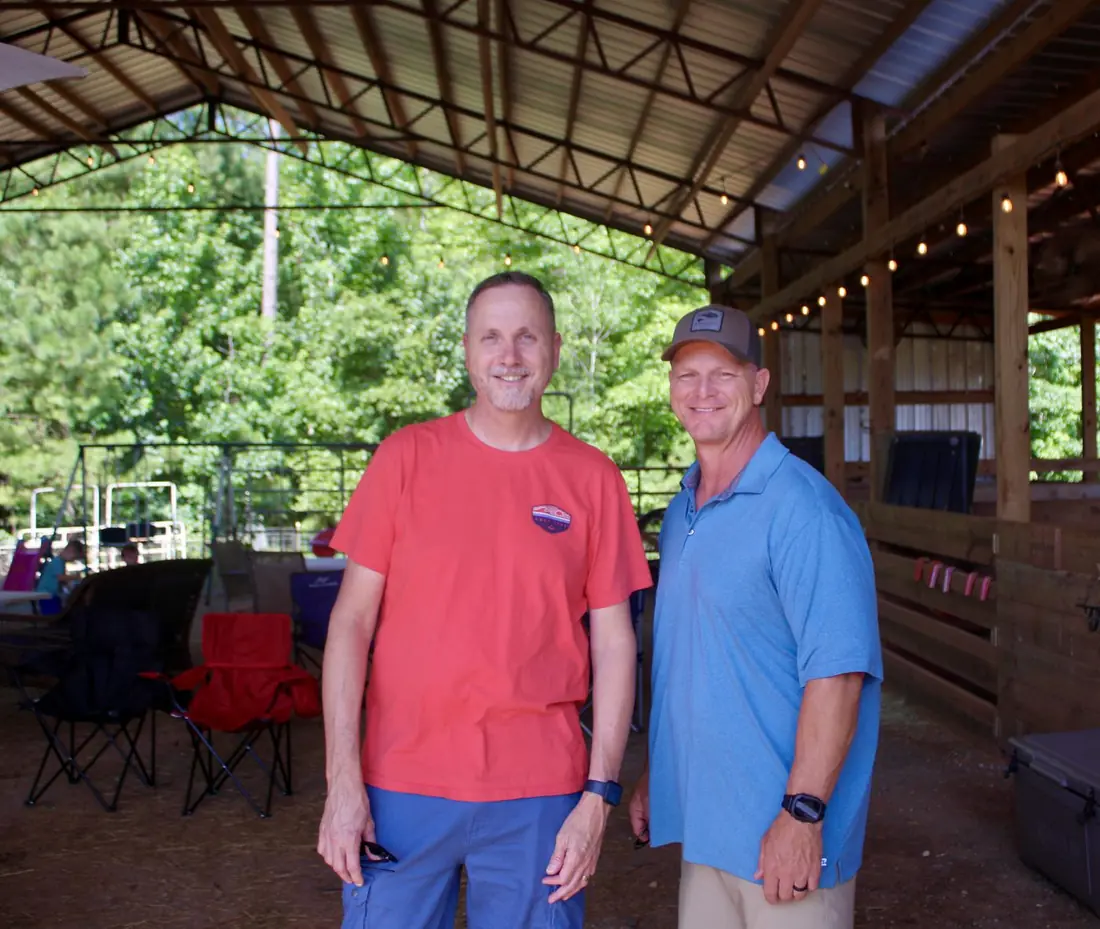 Two men smiling together under the barn pavilion