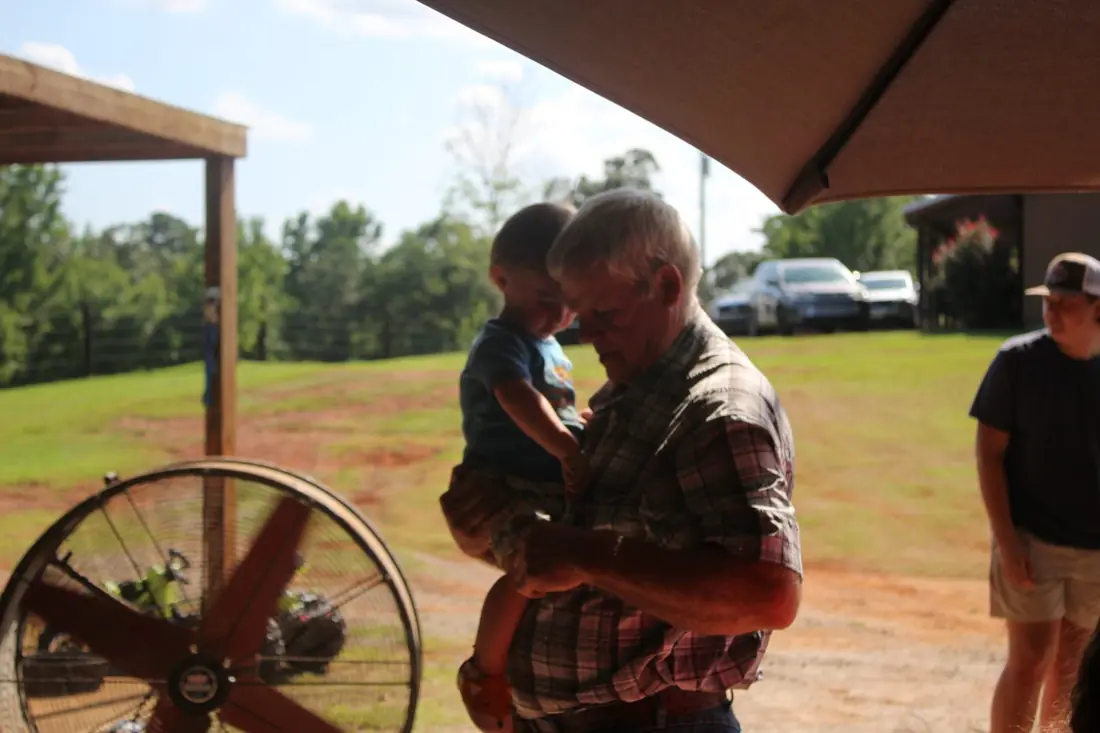 A man holding a small child in the shade